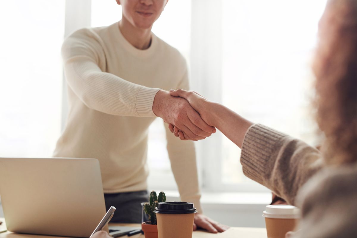 Two business partners shaking hands over a desk